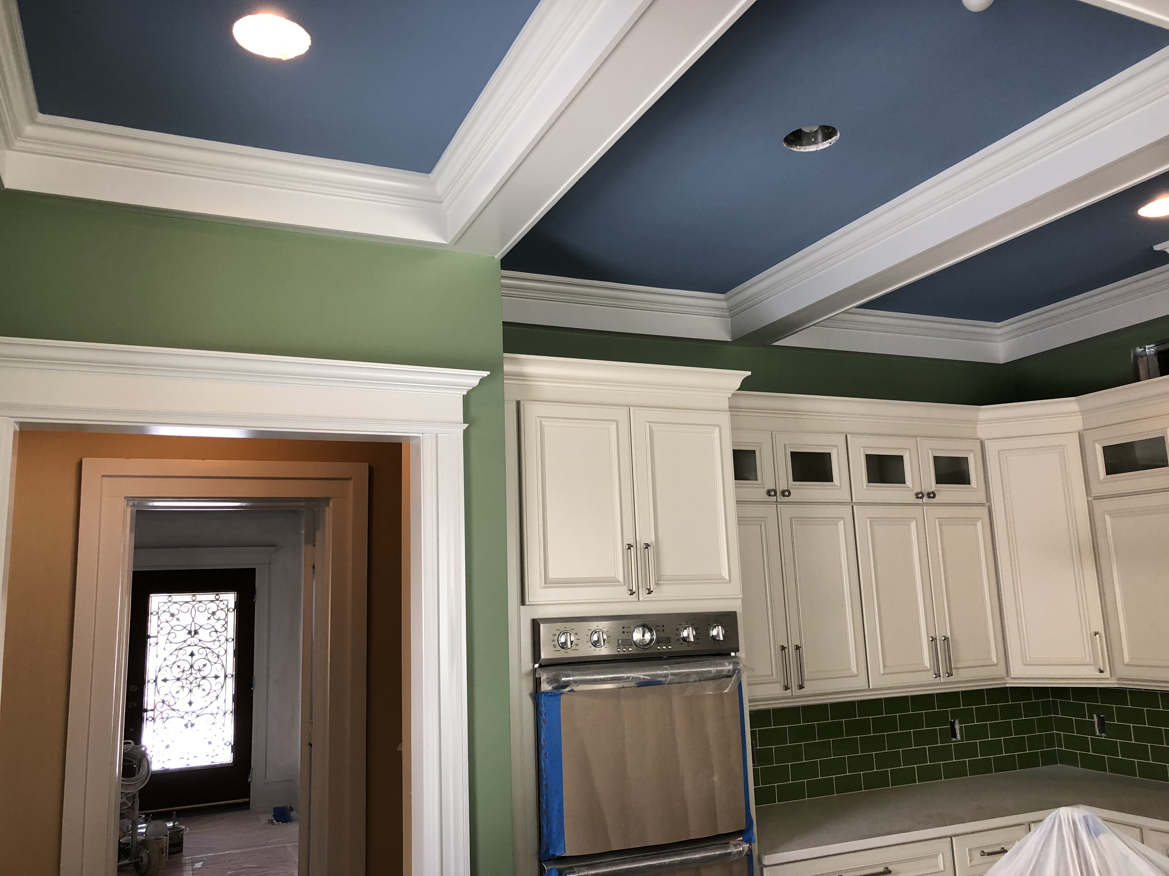 Finished kitchen cabinetry with crisp white trim and blue coffered ceiling